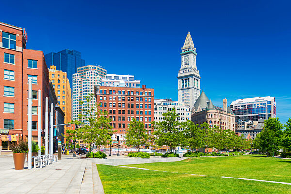 Boston - Juni 2016, MA, USA: Blick auf den Custom House Tower, umliegende Gebäude in der Innenstadt und Park mit Bäumen, Rasen und Bänken