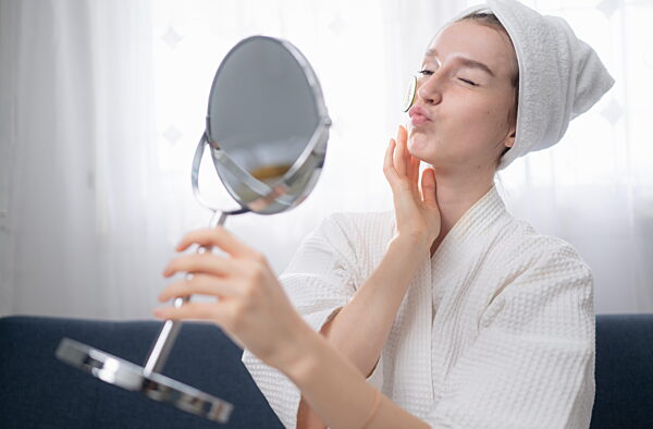 Junge Frau mit natürlichen Aktivitäten zur Gesichtspflege wie Gurken