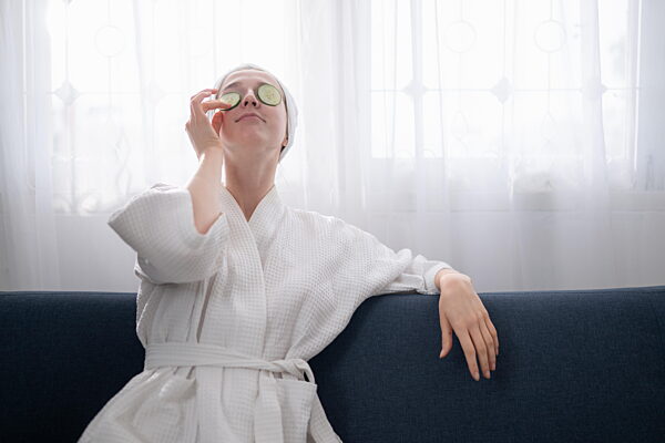 Junge Frau mit natürlichen Aktivitäten zur Gesichtspflege wie Gurken