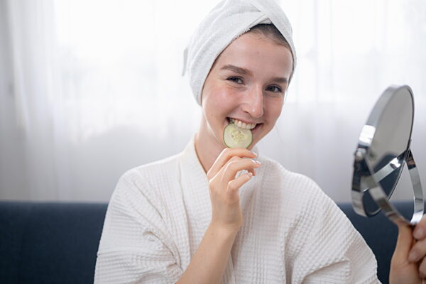 Junge Frau mit natürlichen Aktivitäten zur Gesichtspflege wie Gurken