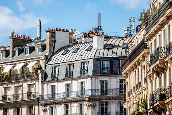 Traditionelle Pariser Dächer mit grauen Zink- und Schieferdetails, klassischen Schornsteinen und schmiedeeisernen Balkonen im 6. Arrondissement.