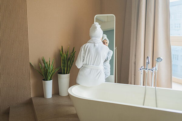 Reife erwachsene alte Frau Blick auf Spiegel Anwendung pflegende Anti-Alter...