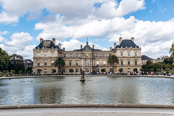 Paris, Frankreich - 12. September 2025: Der Luxemburg-Palast, Sitz des französischen Senats, spiegelt sich im großen Teich des Jardin du Luxembourg bei teilweise bewölktem Himmel.