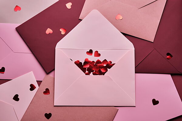 Streuung von rotem Herzkonfetti aus einem Liebesbriefumschlag