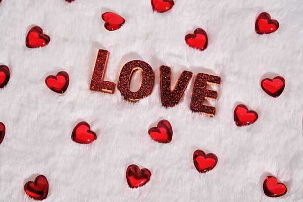 Die Aufschrift ist LOVE auf einem weißen Plüschhintergrund mit Herzen. Hintergrund.