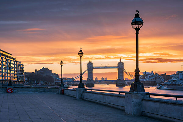 Tower Bridge framed by lamp posts at sunrise.