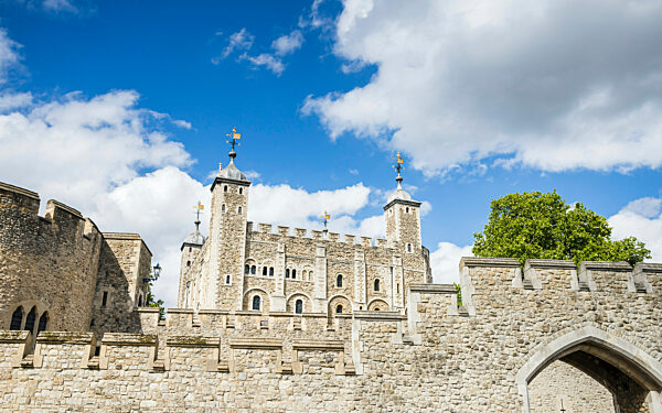 Looking up at the Tower of London pictured under a bright blue sky.