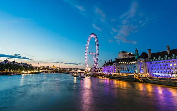 Beautiful tones from the lights on the London Aquarium and the London Eye reflect on the River Thames in London.