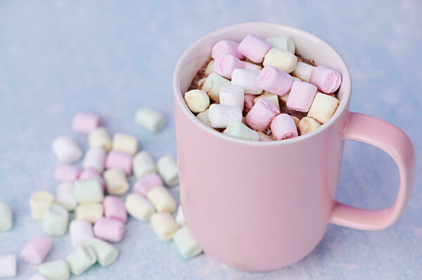 Pink Cup With Hot Chocolate, In It Many Small Colorful Marshmallows On Blue Background