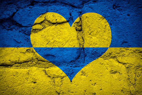 Ukraine Flagge in Landesfarbe Gelb Blau in Herz Form auf einer Steinwand, Symbol für Friede Hoffnung und Beten für den Krieg in der Ukraine FOTOMONTAGE