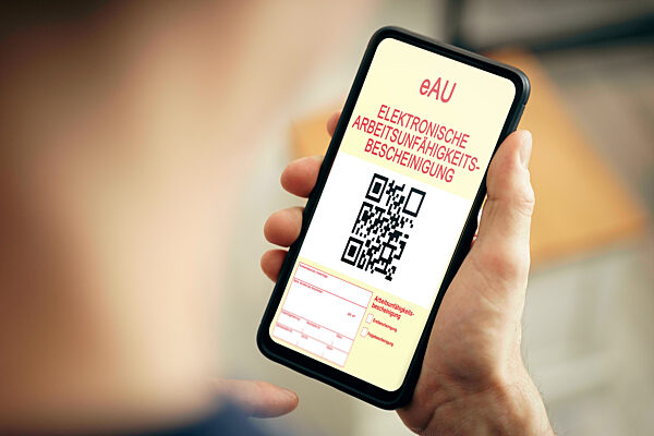 Mann hält Smartphone mit einer eAU Elektronischen Arbeitsunfähigkeitsbescheinigung in der Hand. Elektronische Krankmeldung FOTOMONTAGE