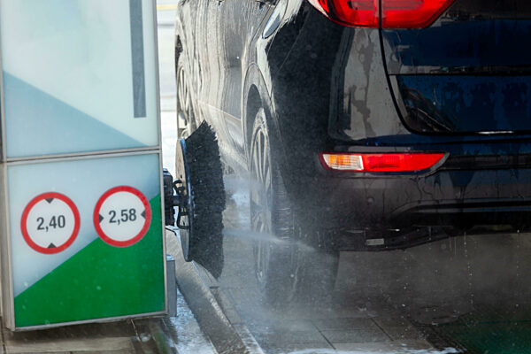 Schwarzes Auto wird in einer automatischen Waschanlage mit Bürsten und Seife gewaschen