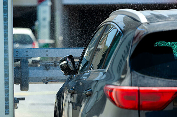Ein modernes Auto wird an einem strahlenden Sommertag in einer automatischen Waschanlage gewaschen
