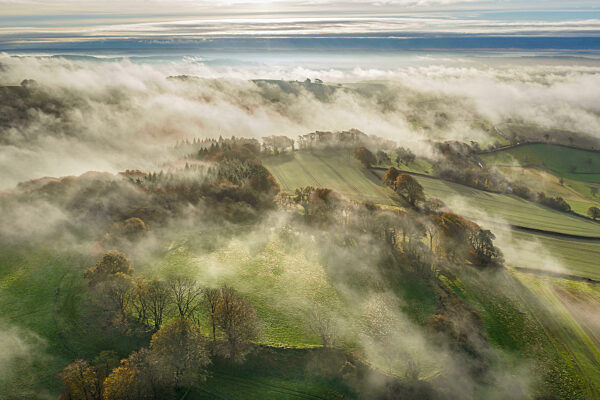 Misty autumn morning above Cadbury Castle Iron Age Hillfort, Cadbury, Devon, England. Autumn (November) 2021.