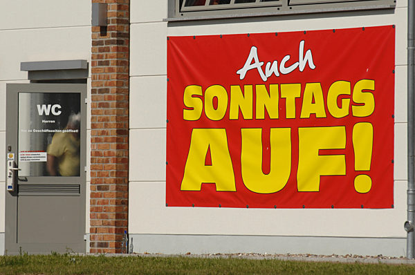 Neben dem Eingang zu einer Toilette hängt ein großes Plakat mit der...