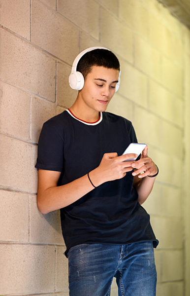 teenager;smiling;typing;headphones;smart phone;listening music