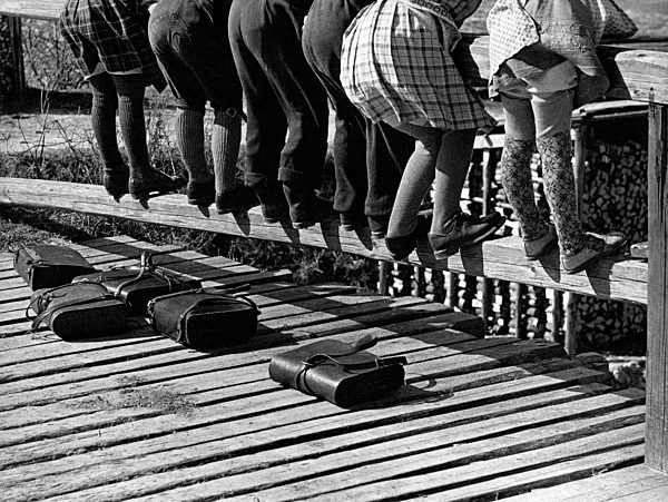 Blick auf die Beine von Schulkindern, die sich über ein Brückengeländer beugen, 50er Jahre