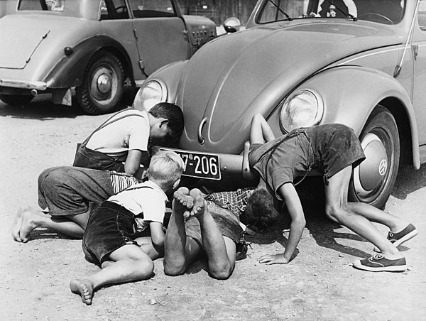 Buben schauen unter einen VW-Käfer, 50er Jahre