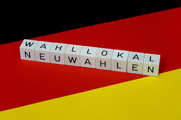 Deutschlandfahne mit Buchstabenwuerfel und Schriftzuege Neuwahlen und Wahllokal