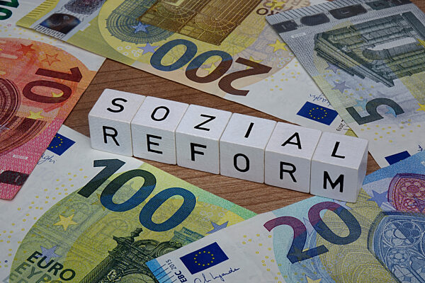 Geldscheine und Buchstabenwuerfel mit Sozialreform