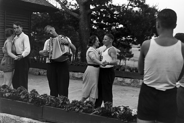 Musik und Tanz vor Waldhütten des KdF Sportheim Belzig in der Mark Brandenburg; Deutschland 1930er Jahre. People singing and dancing in front of forest huts at the sports club at Belzig in Brandenburg; Germany 1930s.