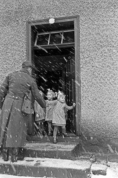 Der Vater begrüßt seine Vierlinge auf Weihnachtsurlaub im Schnee; Deutschland 1930er Jahre. Father of the quadruplet girls on christmas holiday from the army in the snow saying hello to his girls; Germany 1930s.