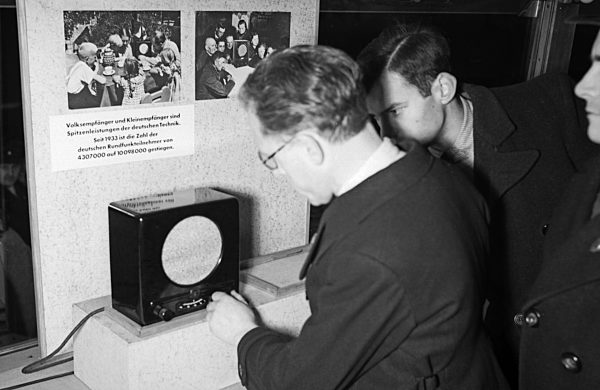 Ausstellungsbesucher informieren sich auf der "Sudetenfahrt der deutschen Technik" über die neuesten deutschen Errungenschaften auf dem Gebiet der Technik; hier das Volksempfänger Radio; Deutschland 1930er Jahre