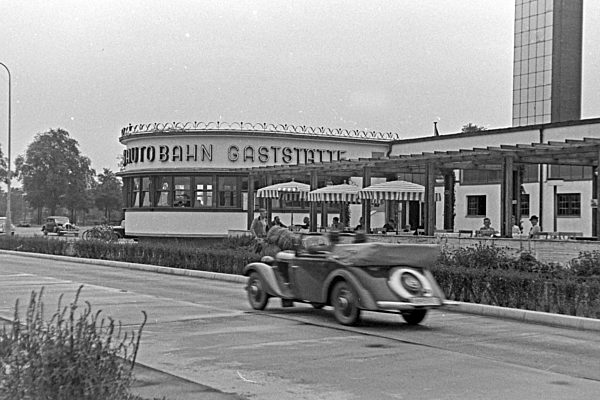 Ein Cabrio fährt an einer Reichsautobahngaststätte vorbei; Deutschland 1930er Jahre. A convertible passing a Reichsautobahn highway roadhouse; Germany 1930s.