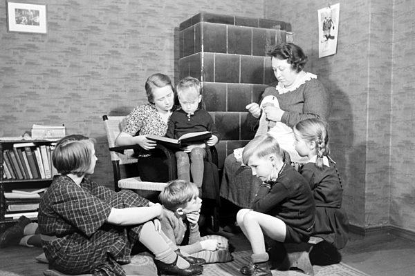 Mitglieder einer kinderreichen Familie lesen gemeinsam ein Buch; Deutsches Reich 1930er Jahre. Members of a extended family reading a book together; Germany 1930s.