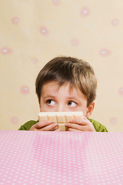 Close-up of a boy holding a bar of white chocolate