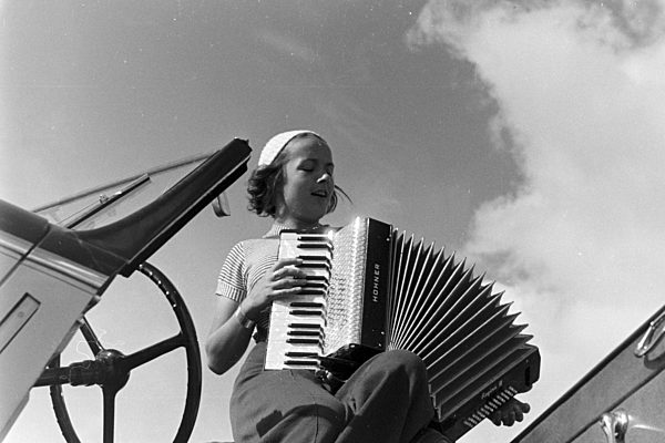 Eine junge Frau beim Harmonika-Spiel; Deutsches Reich 1930er Jahre. A young woman playing the harmonica; Germany 1930s.