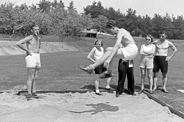 Übung im Weitsprung auf dem Sportplatz des KdF Sportheim Belzig in der Mark Brandenburg; Deutschland 1930er Jahre. Long jump exercising at the sports ground of the sports club house at Belzig in Brandenburg; Germany 1930s.