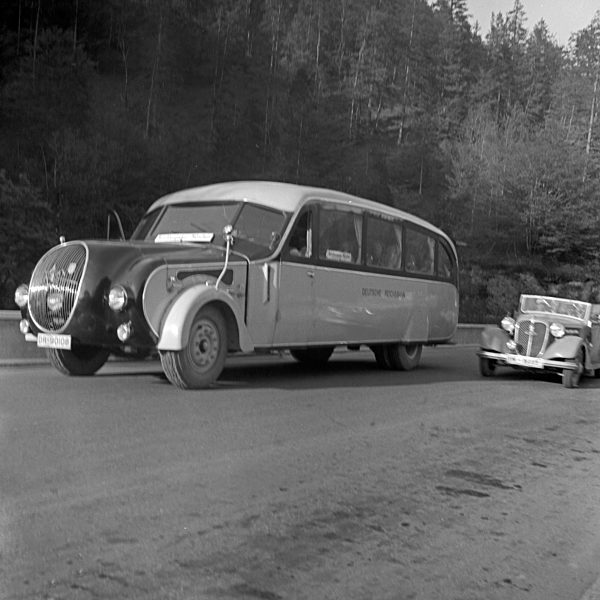 Ein PKW überholt einen Bus der Deutschen Reichsbahn auf der Reichsautobahn zwischen München und Berchtesgaden; Deutschland 1930er Jahre. A convertible overtaking a bus of the Deutsche Reichsbahn on the Reichsautobahn highway between Munich and Berchtesga