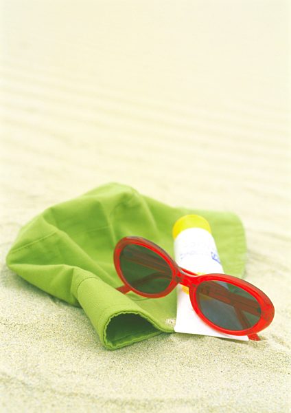 Sunglasses, sunscreen and sun hat on beach