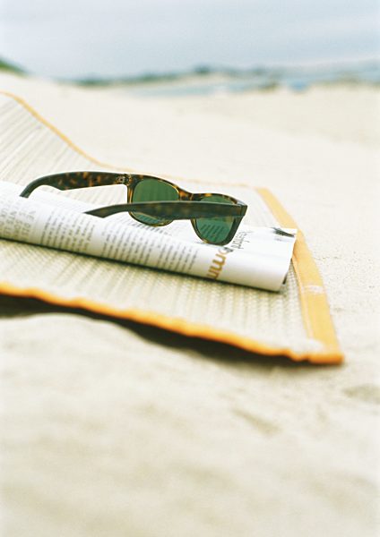 Sunglasses and magazine on beach mat