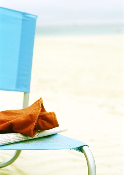 Newspaper and piece of clothing on beach chair