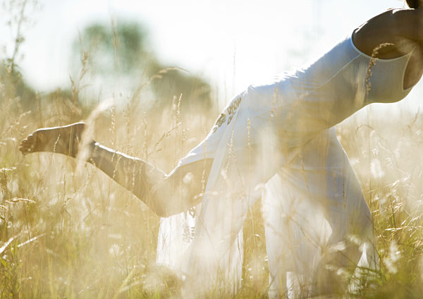 Woman exercising in field, in lunge position, neck down