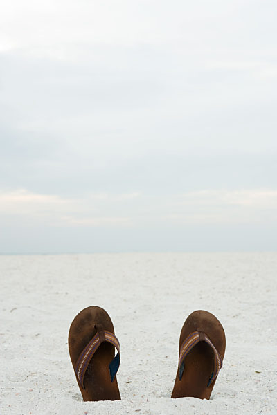 Flipflops half-buried in sand, close-up