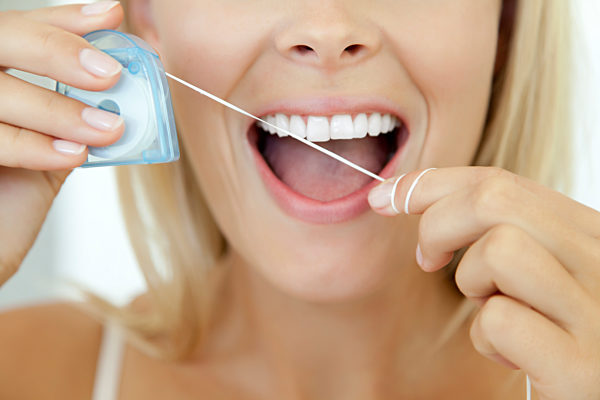 Woman using dental floss, cropped