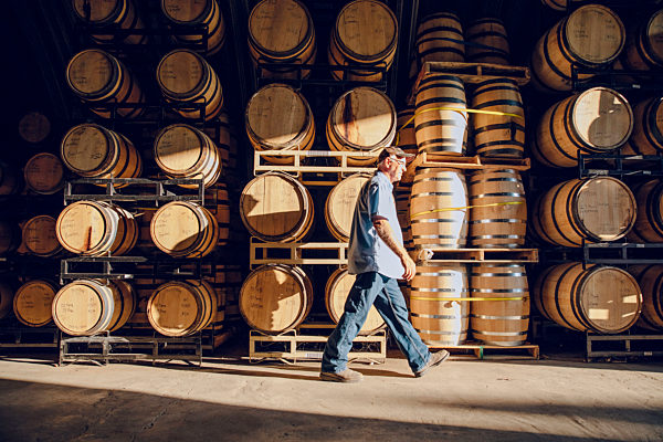 Caucasian man walking near barrels in distillery, Kaukasischer Mann zu Fuss in der Naehe von Faessern in Brennerei