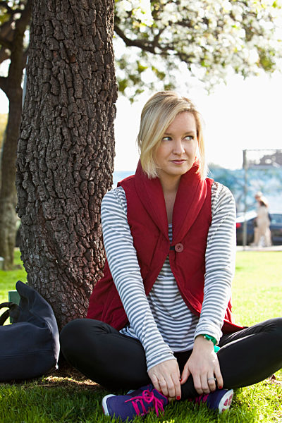 Caucasian woman sitting by tree in park, Kaukasische Frau durch Baum im Park sitzt