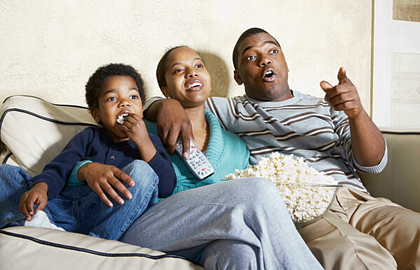 Afroamerikanische Familie vor dem Fernseher mit Popcorn, (Aufnahmedatum nicht ?bertragen), African American family watching television with popcorn