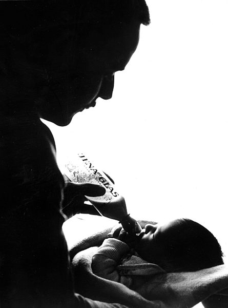 Ein Säugling bekommt von seinem Vater die Flasche...