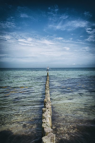 Girl standing on wooden piling piles sea ocean