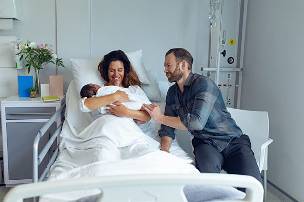 Couple holding their newborn baby in the ward