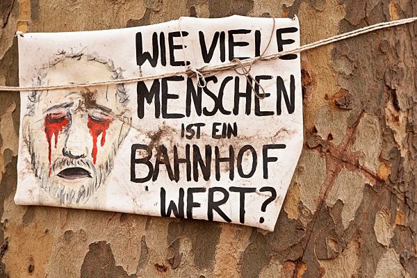 Protestplakat "Wie viele Menschen ist ein Bahnhof wert?" an einem alten Baum gegen das Bahnprojekt Stuttgart 21, Schlossgarten, Stuttgart, Baden-Württemberg, Deutschland, Europa