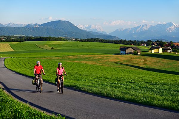 Paar mit E-Bikes am Sulzberg, Obertrum, im Hintergrund die Berchtesgadener Alpen und das Dachsteingebirge, Salzburger Seenland, Salzburger Land, Österreich, Europa