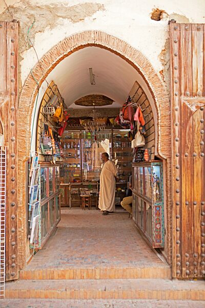 Marokkanischer Mann im Djellaba oder traditionellen Kapuzenmantel steht in einem Laden in der Altstadt, Meknès, Marokko, Afrika