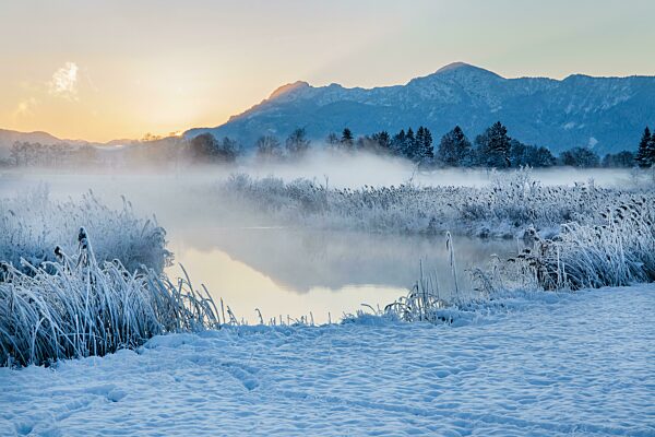 Verschneite Winterlandschaft mit der Uffinger Ach bei Sonnenaufgang mit Herzogstand 1731m und Heimgarten 1790m, Uffing am Staffelsee, Das Blaue Land, Oberbayern, Bayern, Deutschland, Europa