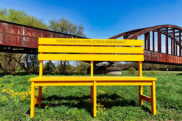 Überdimensionale gelbe Holzbank vor alter Eisenbahnbrücke, Aufschrift Willkommen, Kampagne gegen Fachkräftemangel, Standortmarketing, Wirtschaftsförderung, Suche nach Fachkräften, Arbeitskräften, Landesgartenschau 2023, Höxter, Nordrhein-Westfalen,